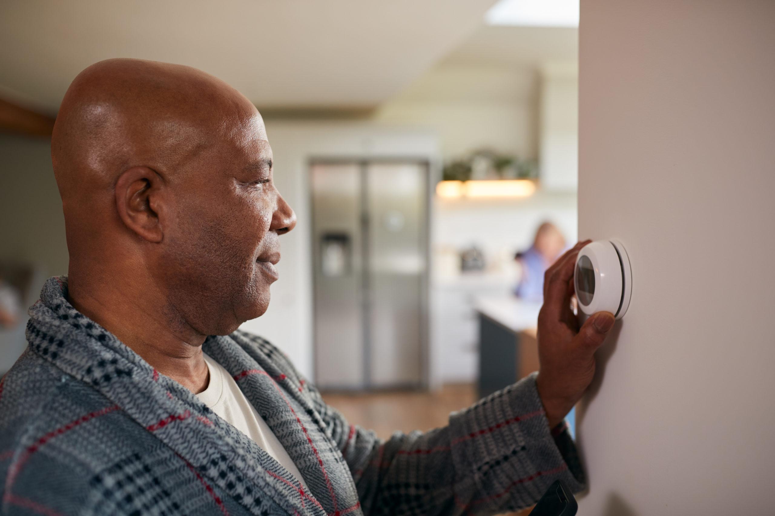 Homeowner adjusting thermostat.